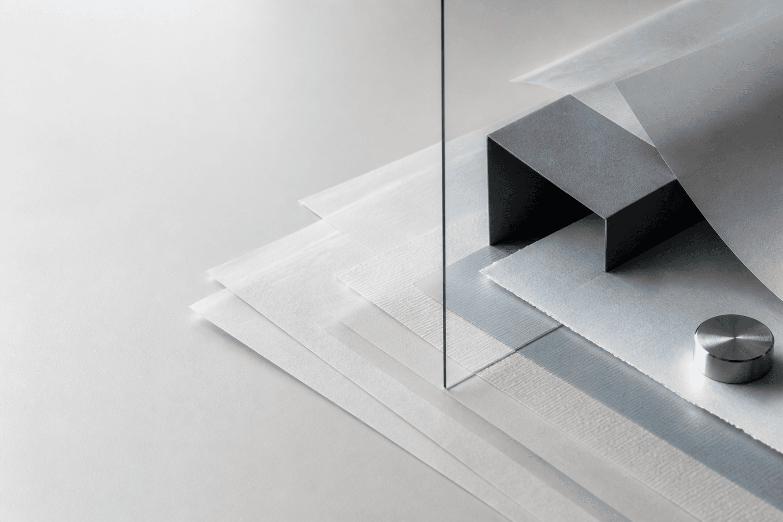 Editorial still life of layered paper, glass, and graphite